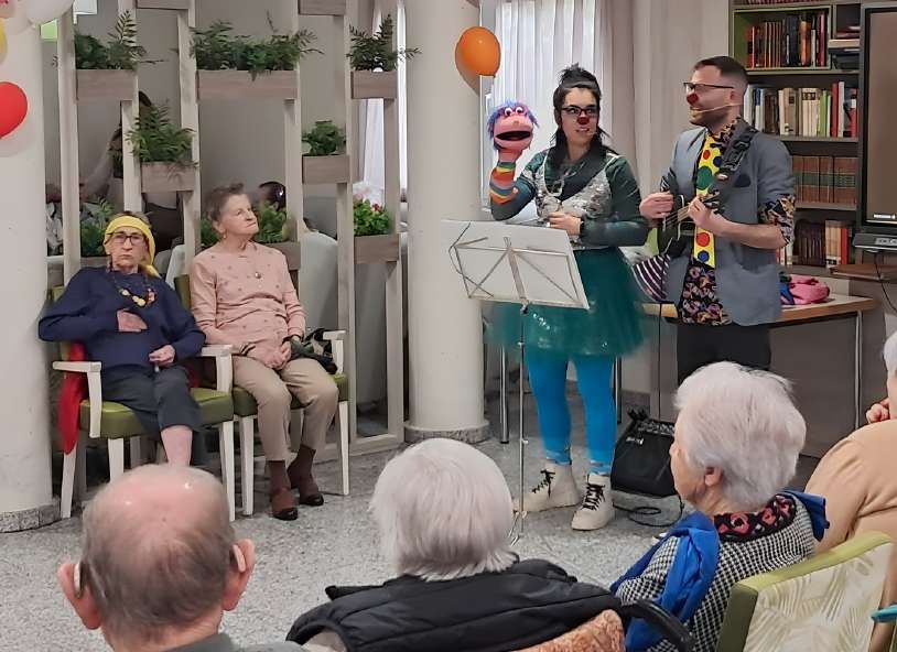 Fiesta teatralizada en una residencia: animadora disfrazada con peluca y músico con guitarra